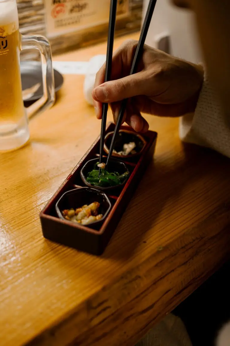 person eating Japanese food with chopsticks and beer