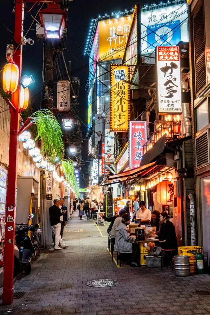 lively Tokyo alley at night with neon signs and people dining